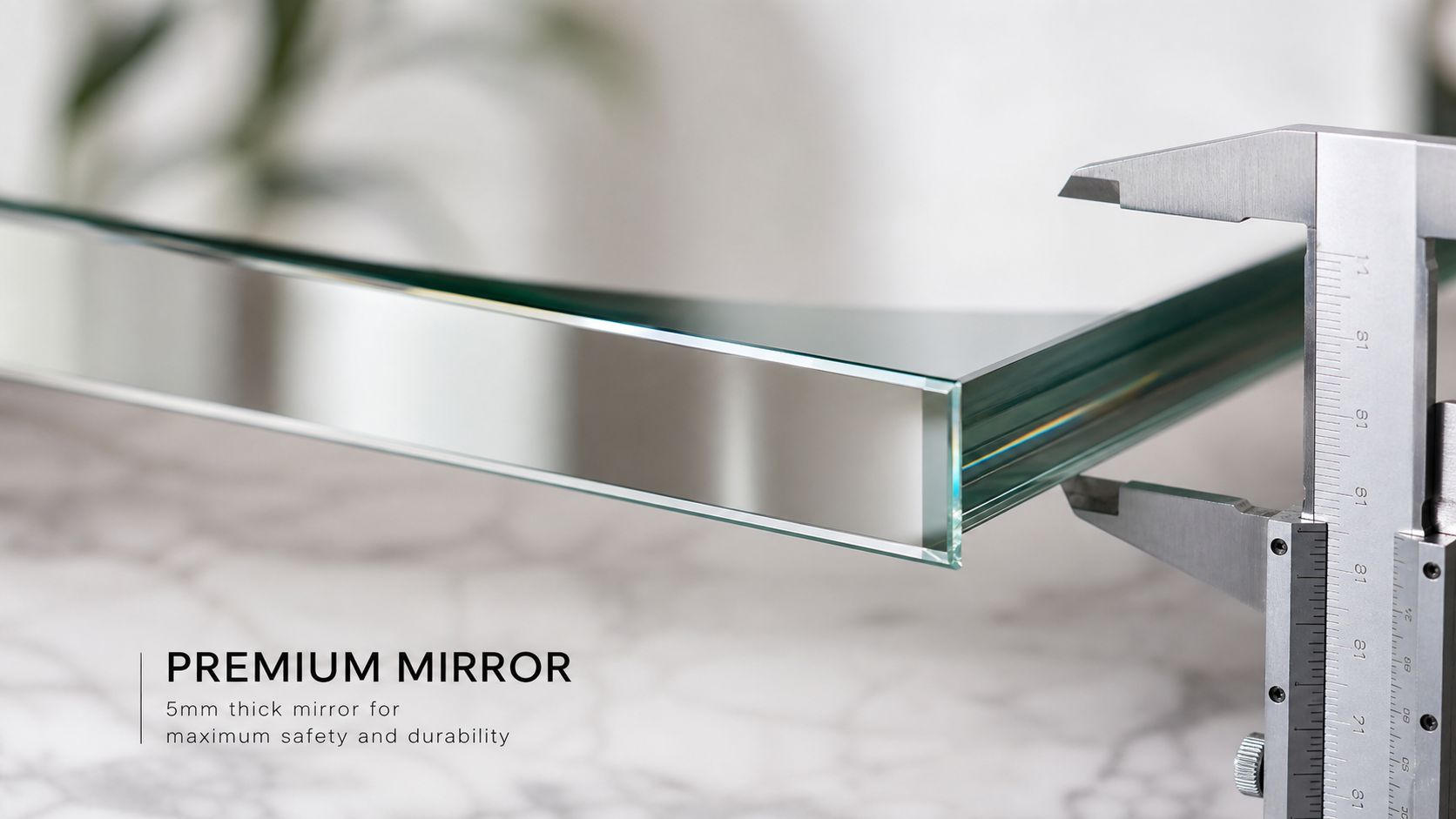 A close up view of a thick glass mirror being measured by a metal caliper on a table.